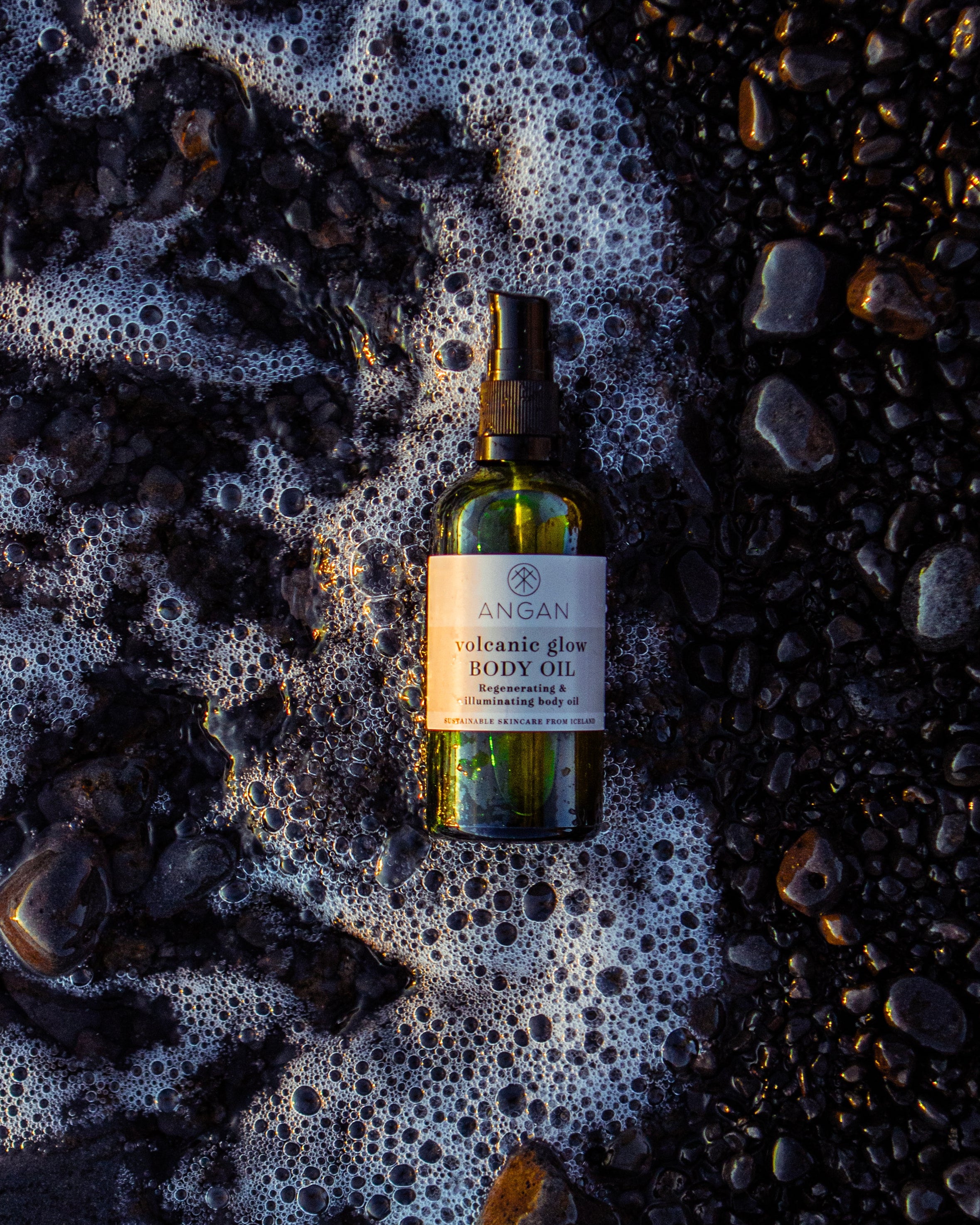 ANGAN Volcanic Glow Body Oil — lifestyle shot at golden hour on the beach