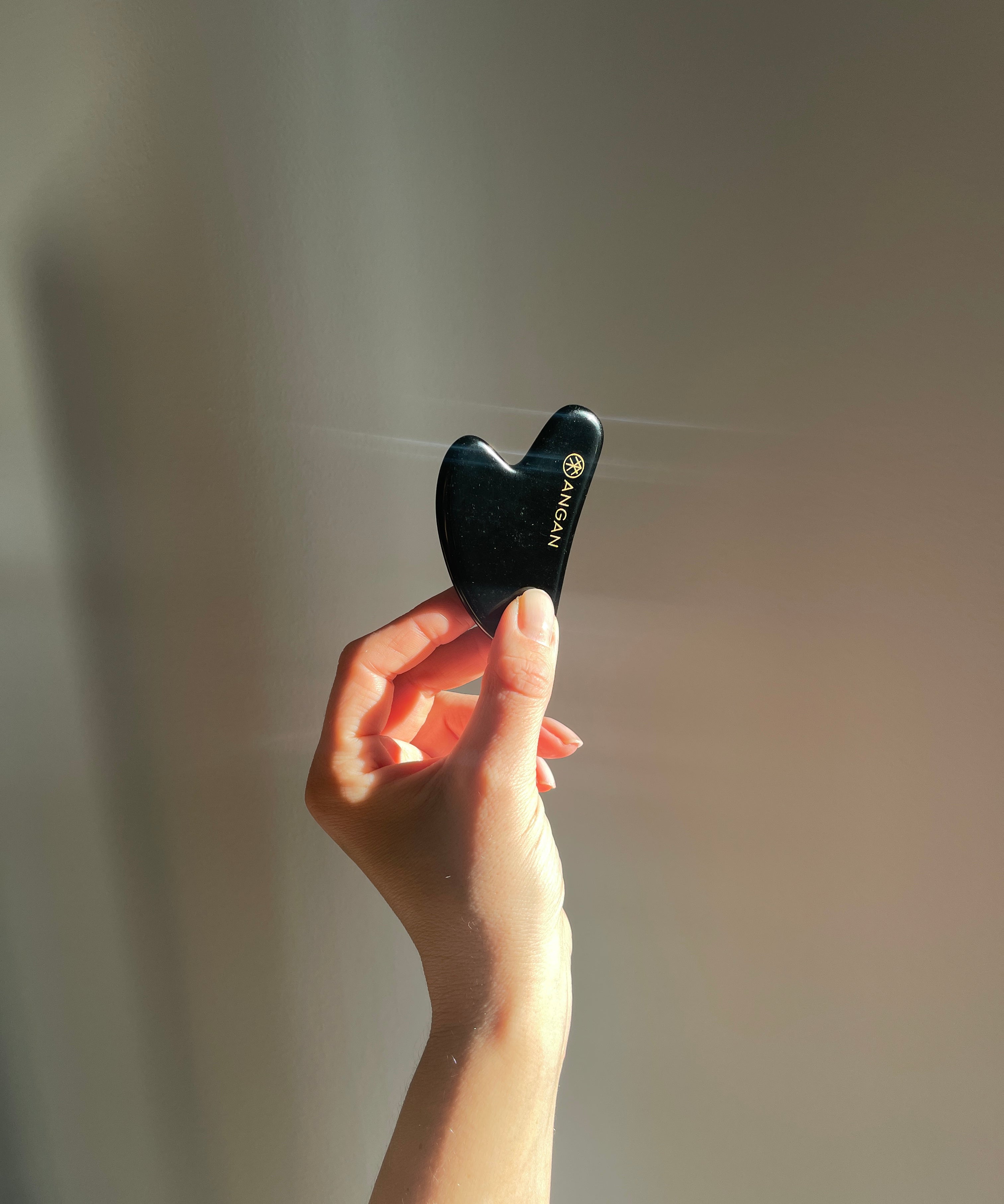 ANGAN Obsidian Gua Sha — in use on skin for facial contouring