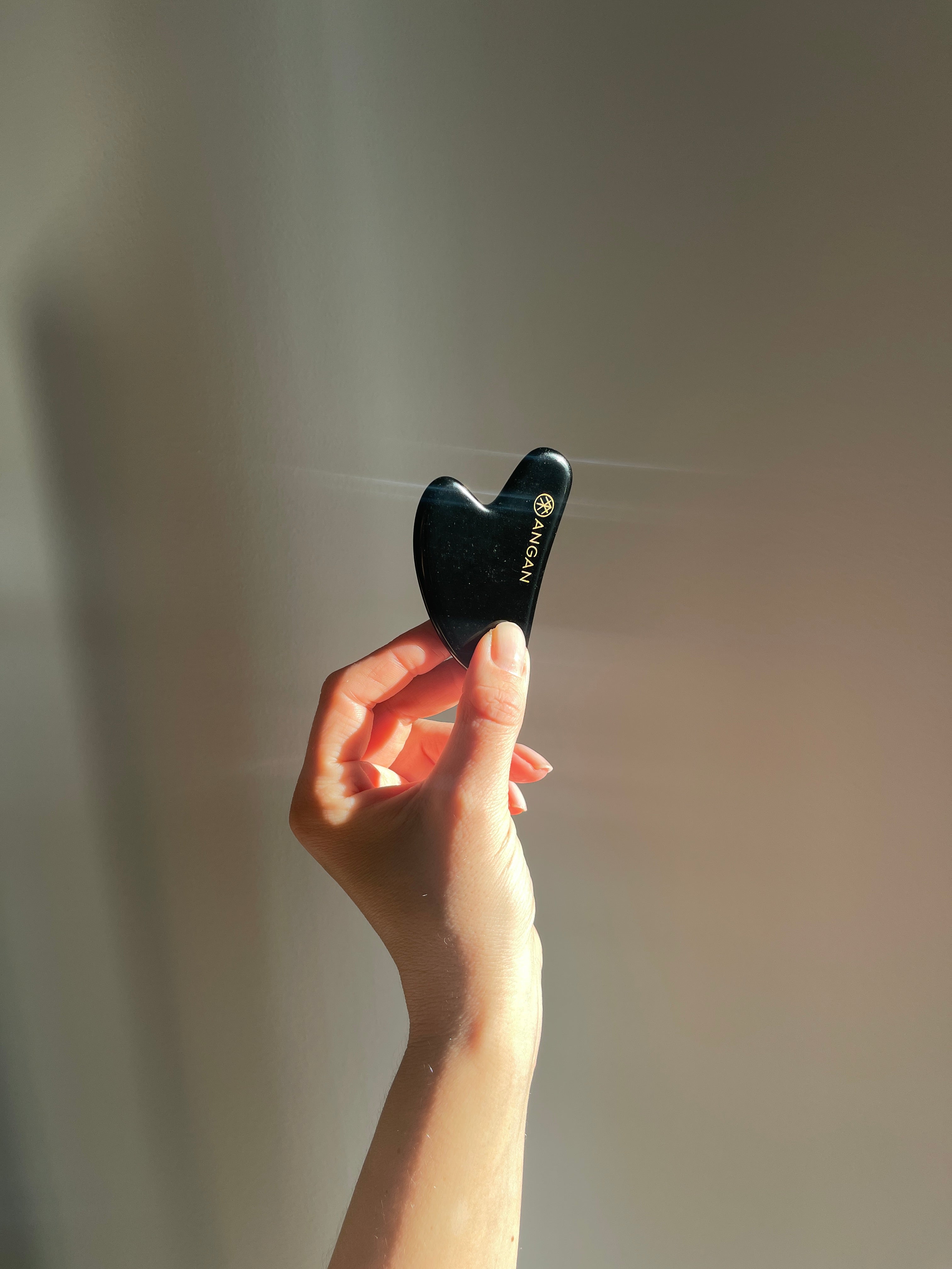 ANGAN Obsidian Gua Sha — in use on skin for facial contouring